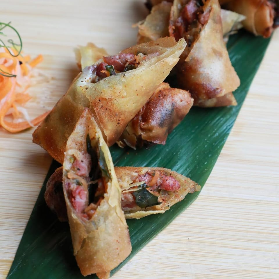 AnQi Bistro's crispy Asian-fusion spring rolls, some cut open to show the savory filling, on a banana leaf.
