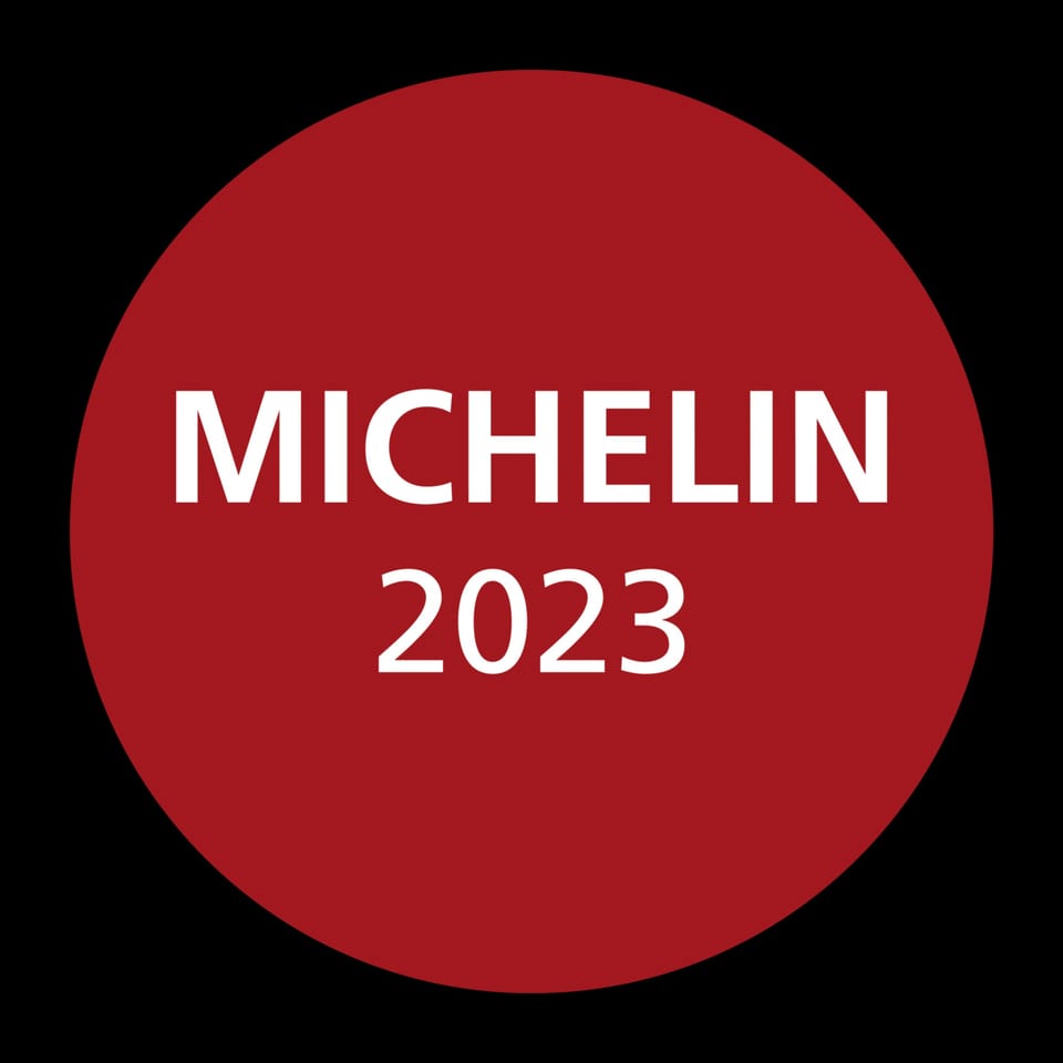 Red circular Michelin Guide 2023 award logo on a black background.
