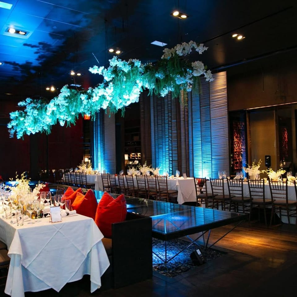 AnQi Bistro's elegant dining room with long tables, white tablecloths, and blue-lit floral decor.